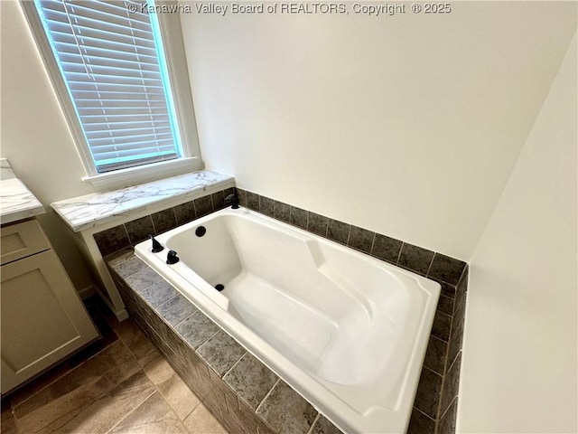 bathroom with tile patterned floors, vanity, and tiled bath