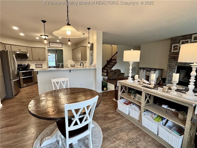 dining area featuring a stone fireplace and dark hardwood / wood-style floors