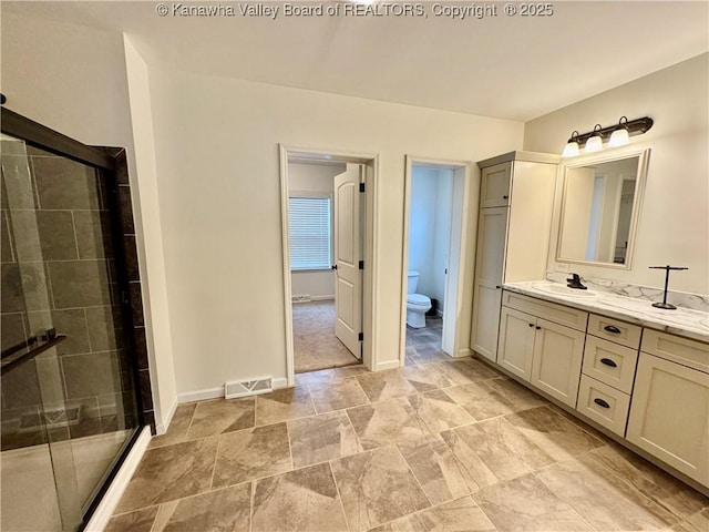 bathroom featuring vanity, an enclosed shower, and toilet