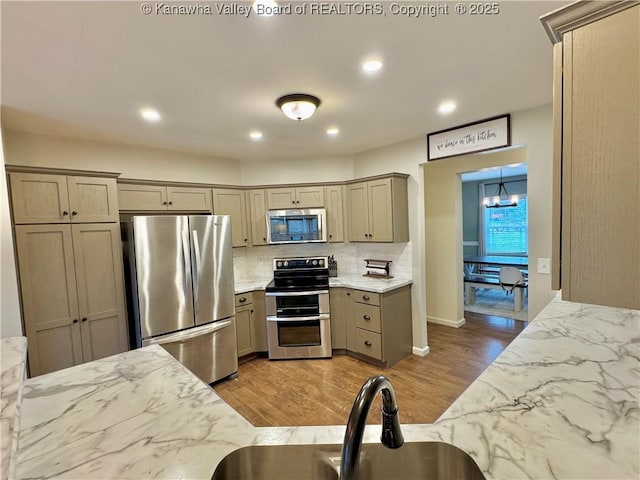 kitchen with decorative backsplash, stainless steel appliances, light hardwood / wood-style floors, and sink