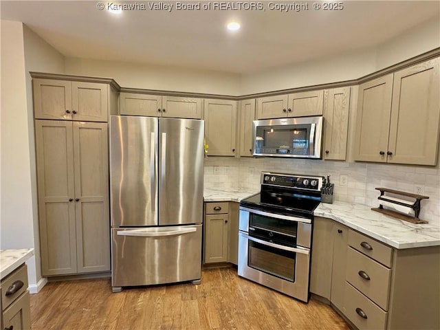 kitchen featuring light stone countertops, backsplash, stainless steel appliances, and light hardwood / wood-style floors