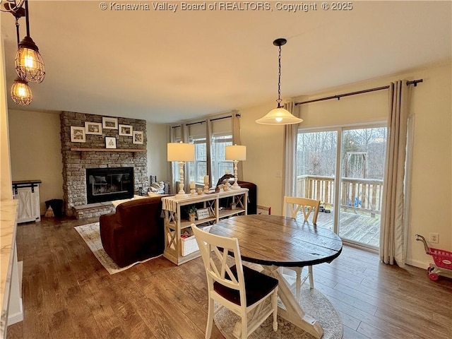 dining space with hardwood / wood-style floors and a stone fireplace