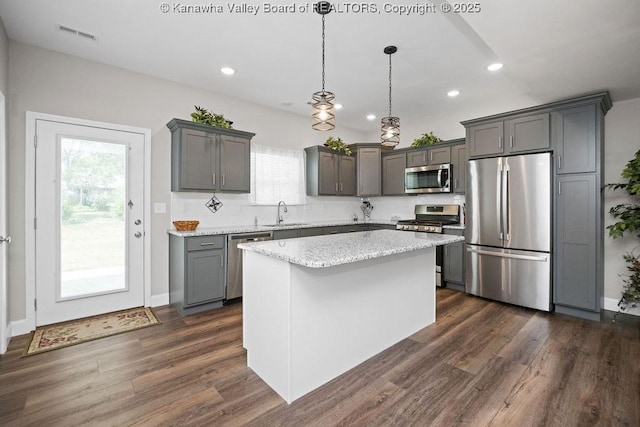 kitchen featuring pendant lighting, dark hardwood / wood-style floors, a kitchen island, and stainless steel appliances