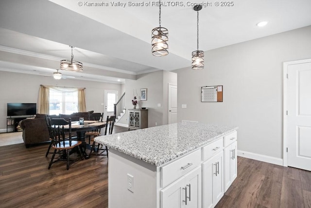 kitchen featuring ceiling fan, a kitchen island, dark hardwood / wood-style floors, pendant lighting, and white cabinets