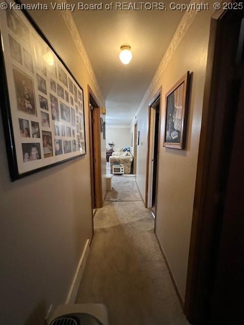 hall with crown molding and light carpet