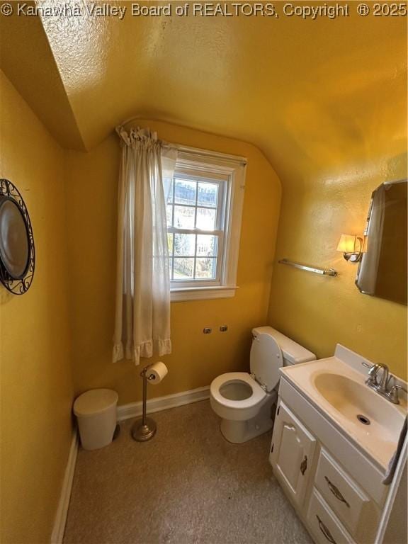 bathroom with lofted ceiling, vanity, a textured ceiling, and toilet