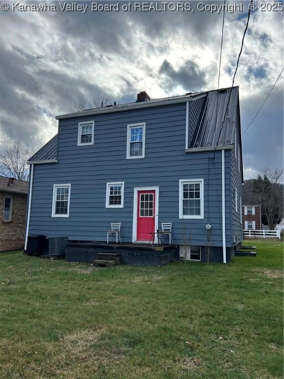 rear view of property with central AC and a yard