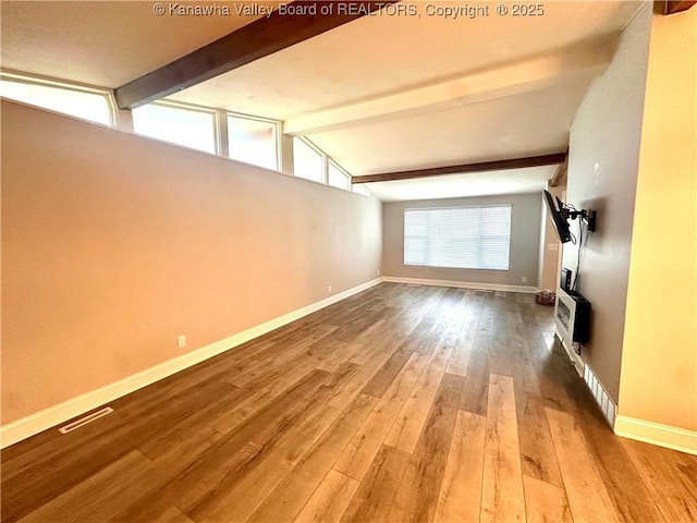 unfurnished living room featuring vaulted ceiling with beams and hardwood / wood-style floors