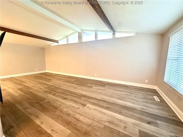 additional living space with wood-type flooring and lofted ceiling with beams