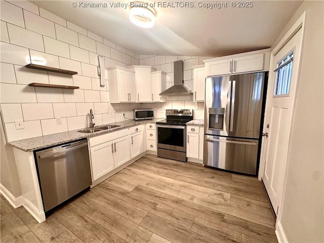 kitchen featuring wall chimney exhaust hood, sink, white cabinetry, and stainless steel appliances