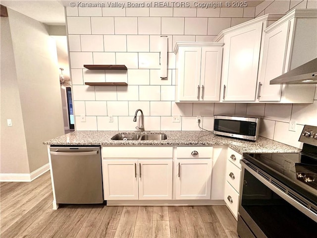 kitchen with white cabinets, sink, light hardwood / wood-style flooring, light stone countertops, and stainless steel appliances