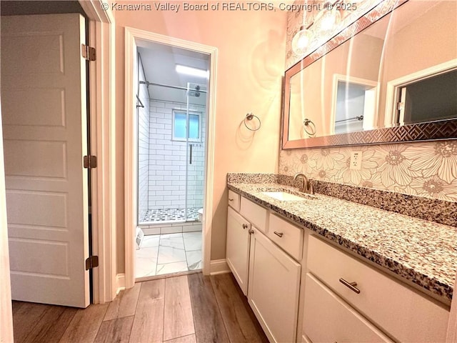 bathroom featuring backsplash, hardwood / wood-style floors, vanity, and an enclosed shower