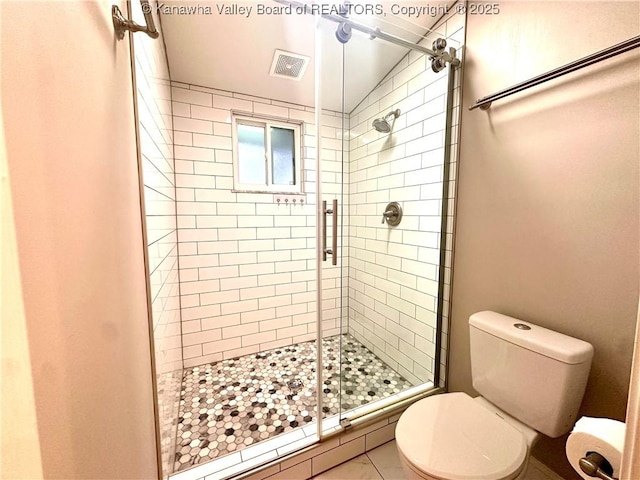 bathroom featuring tile patterned floors, a shower with door, and toilet