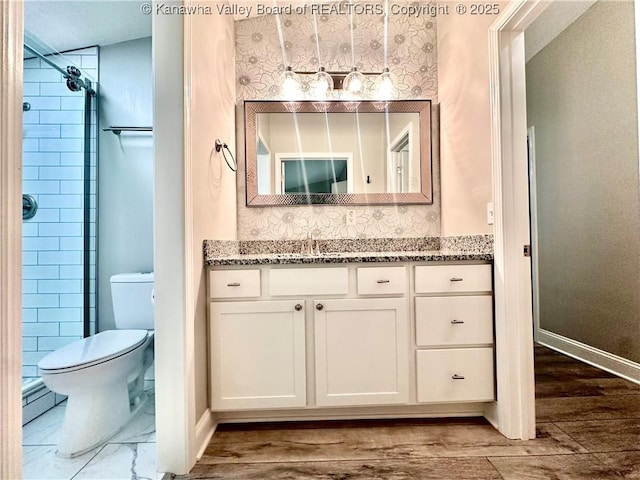 bathroom featuring hardwood / wood-style flooring, toilet, a tile shower, and vanity