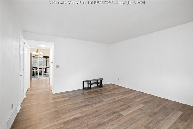 unfurnished room with a chandelier and wood-type flooring