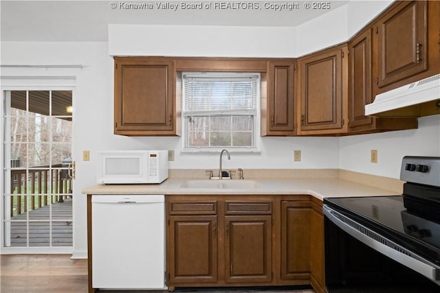 kitchen with sink, white appliances, and hardwood / wood-style flooring