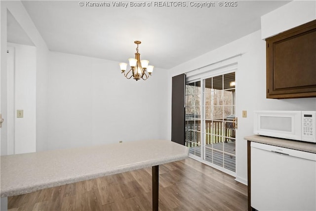 unfurnished dining area with a chandelier and hardwood / wood-style flooring