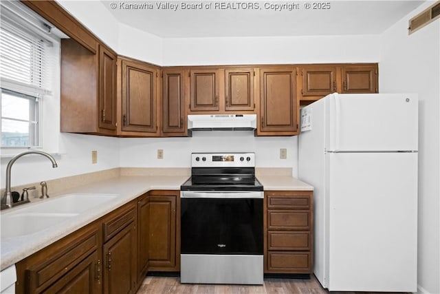 kitchen featuring white refrigerator, stainless steel range with electric cooktop, and sink