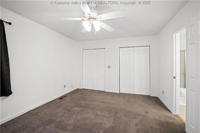 unfurnished bedroom featuring connected bathroom, ceiling fan, two closets, and dark colored carpet