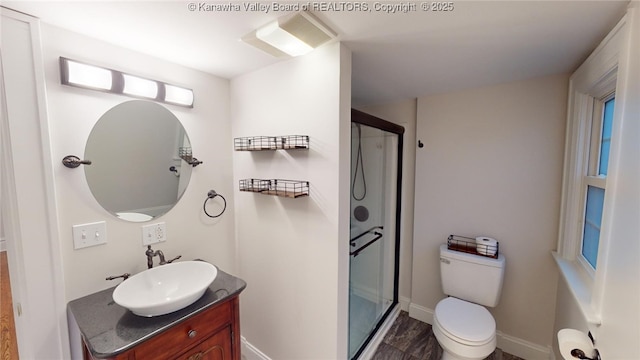 bathroom with hardwood / wood-style flooring, vanity, toilet, and a shower with door