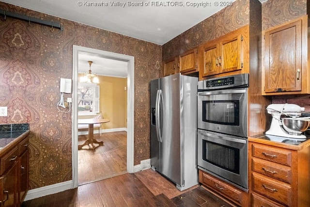 kitchen featuring dark hardwood / wood-style floors, a notable chandelier, and appliances with stainless steel finishes