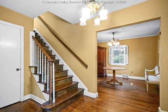 stairway featuring hardwood / wood-style flooring, crown molding, and an inviting chandelier