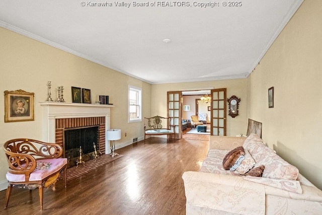 living room with a fireplace, crown molding, french doors, and hardwood / wood-style flooring