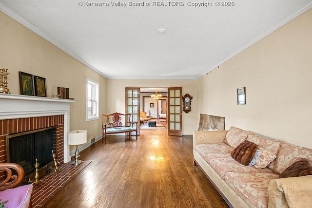 living room with french doors, dark wood-type flooring, a brick fireplace, and crown molding