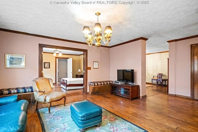 living room featuring a chandelier, wood-type flooring, a textured ceiling, and ornamental molding