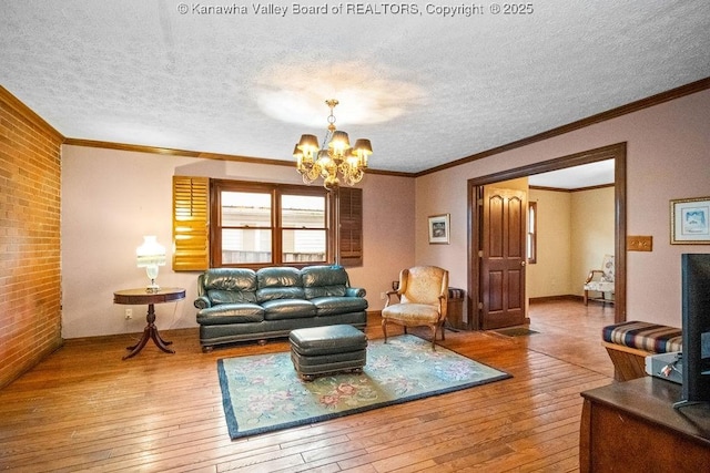 living room featuring ornamental molding, brick wall, a textured ceiling, hardwood / wood-style flooring, and a notable chandelier