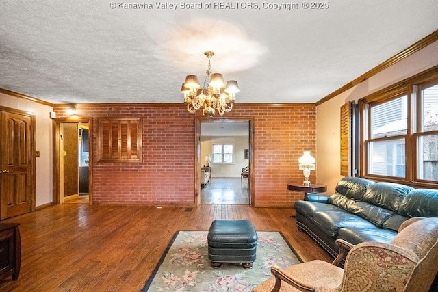 living room featuring wood-type flooring, brick wall, and an inviting chandelier