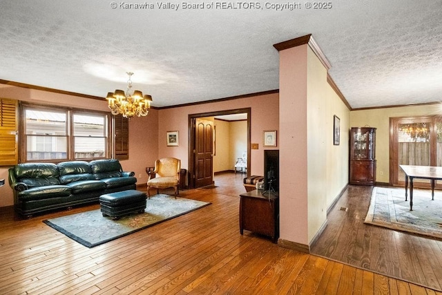 living room featuring crown molding, hardwood / wood-style floors, a textured ceiling, and a notable chandelier