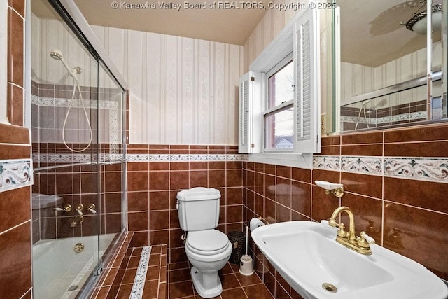 full bathroom with combined bath / shower with glass door, tile patterned floors, sink, tile walls, and toilet