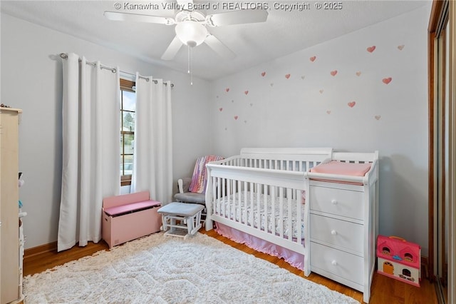 bedroom with ceiling fan, light hardwood / wood-style flooring, and a crib