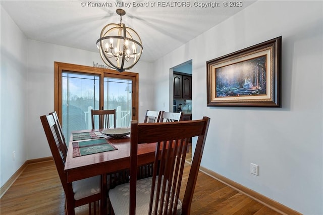 dining room with hardwood / wood-style floors and an inviting chandelier