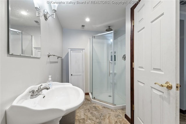 bathroom with a shower with shower door and sink