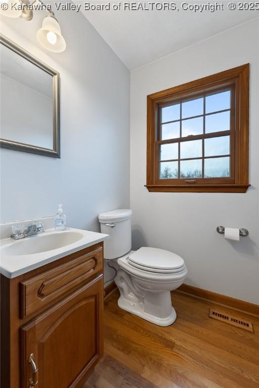 bathroom with hardwood / wood-style floors, vanity, and toilet