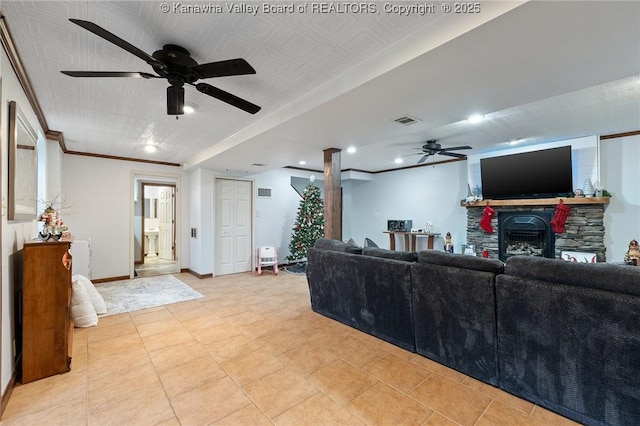 living room featuring ceiling fan, a stone fireplace, and crown molding