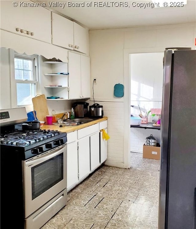 kitchen with white cabinets, sink, appliances with stainless steel finishes, and tile walls