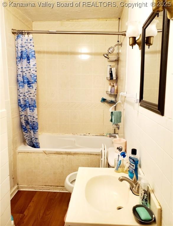 full bathroom featuring hardwood / wood-style floors, toilet, sink, and shower / tub combo