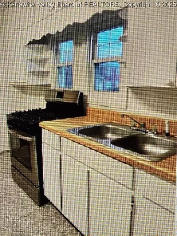 kitchen with gas stove, white cabinetry, and light tile patterned floors