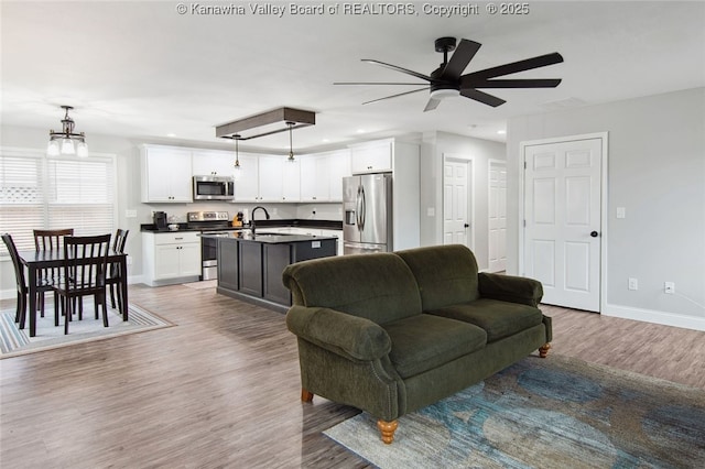 living room with hardwood / wood-style flooring, ceiling fan with notable chandelier, and sink