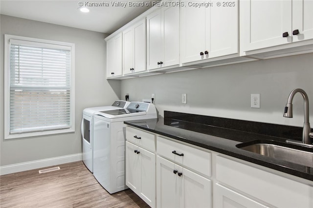 laundry room featuring cabinets, light hardwood / wood-style flooring, washer and clothes dryer, and sink