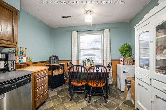 interior space featuring stainless steel dishwasher and wood walls