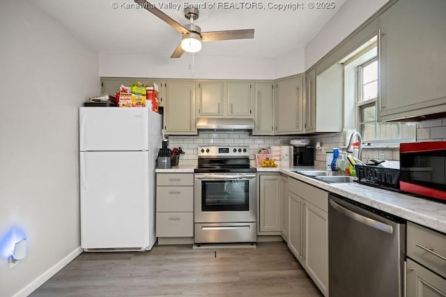 kitchen featuring sink, light hardwood / wood-style flooring, decorative backsplash, ceiling fan, and stainless steel appliances