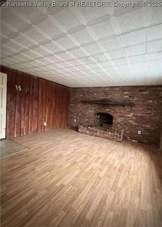 unfurnished living room with wooden walls, a fireplace, and wood-type flooring