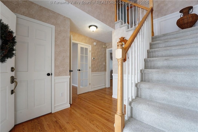 stairway featuring hardwood / wood-style floors, a textured ceiling, and french doors