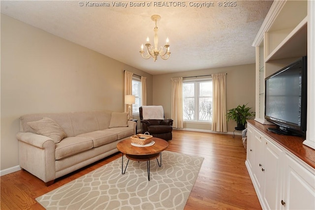 living room featuring a notable chandelier, a textured ceiling, and light hardwood / wood-style flooring