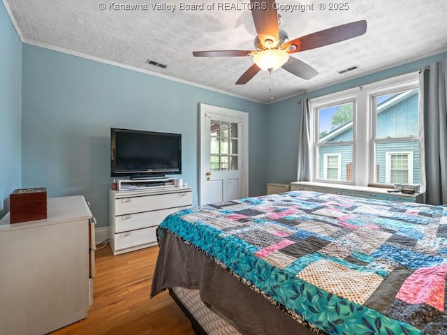 bedroom with ceiling fan, crown molding, a textured ceiling, and light hardwood / wood-style flooring