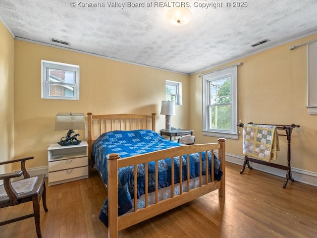 bedroom with light wood-type flooring, a textured ceiling, and ornamental molding